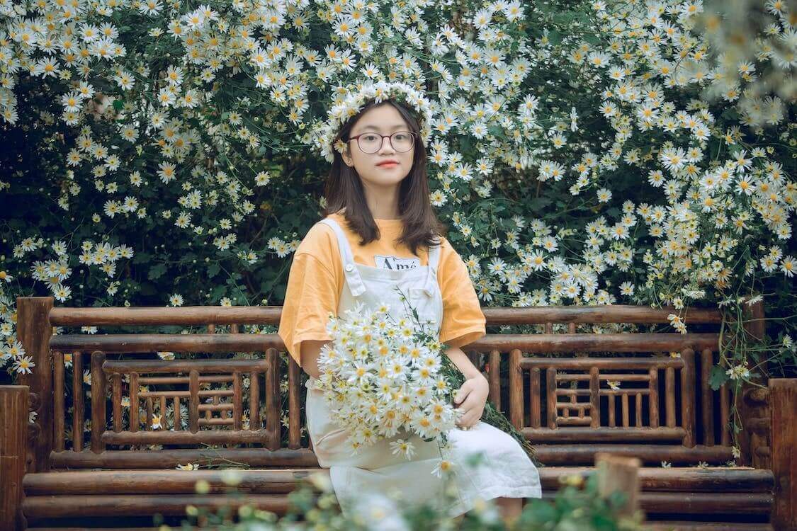 Person holding bouquet of daisies